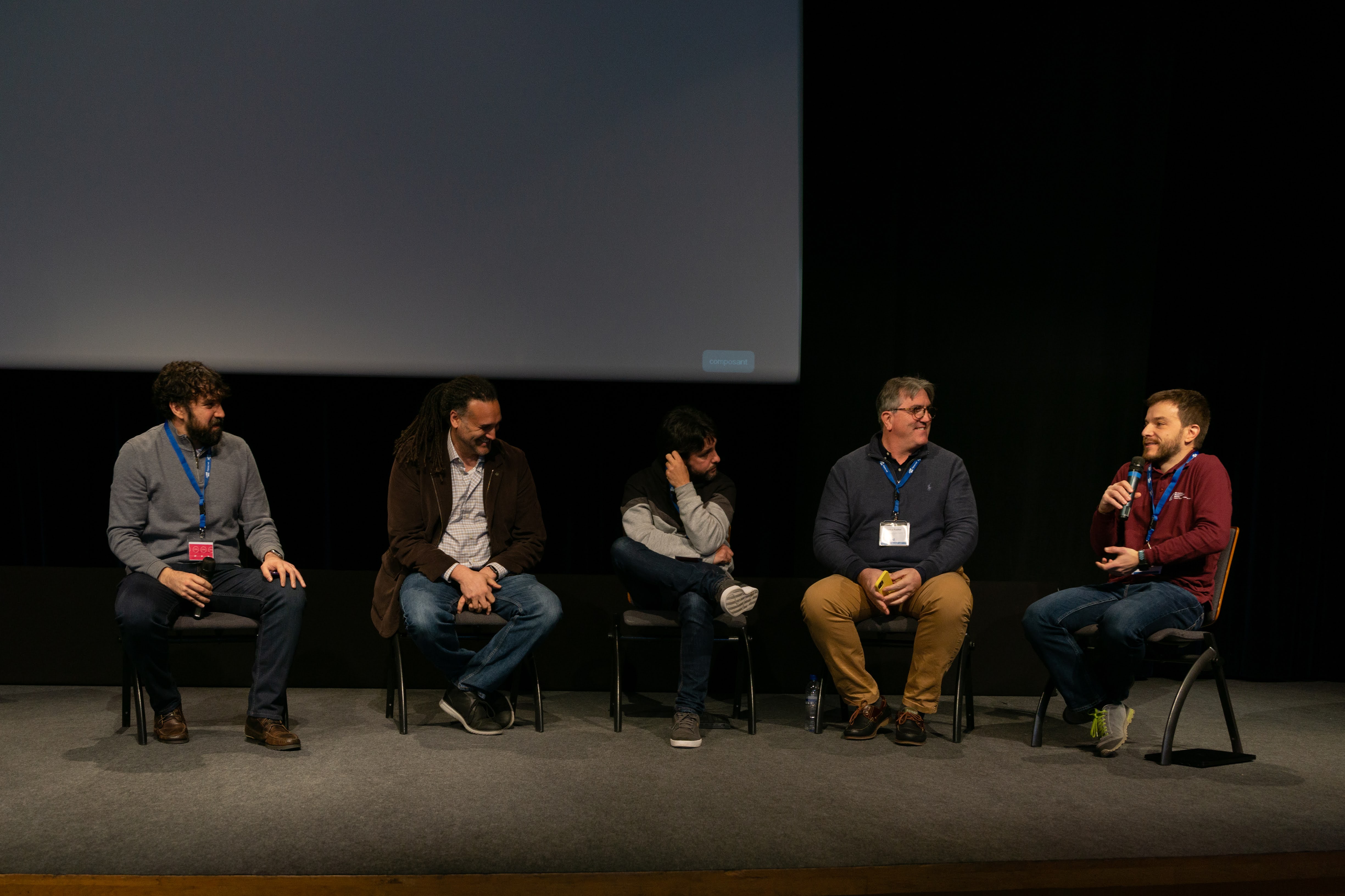 photo of a panel of five men sitting on chairs on a stage. On the right-hand side, Filippo Mantovani is speaking into a microphone