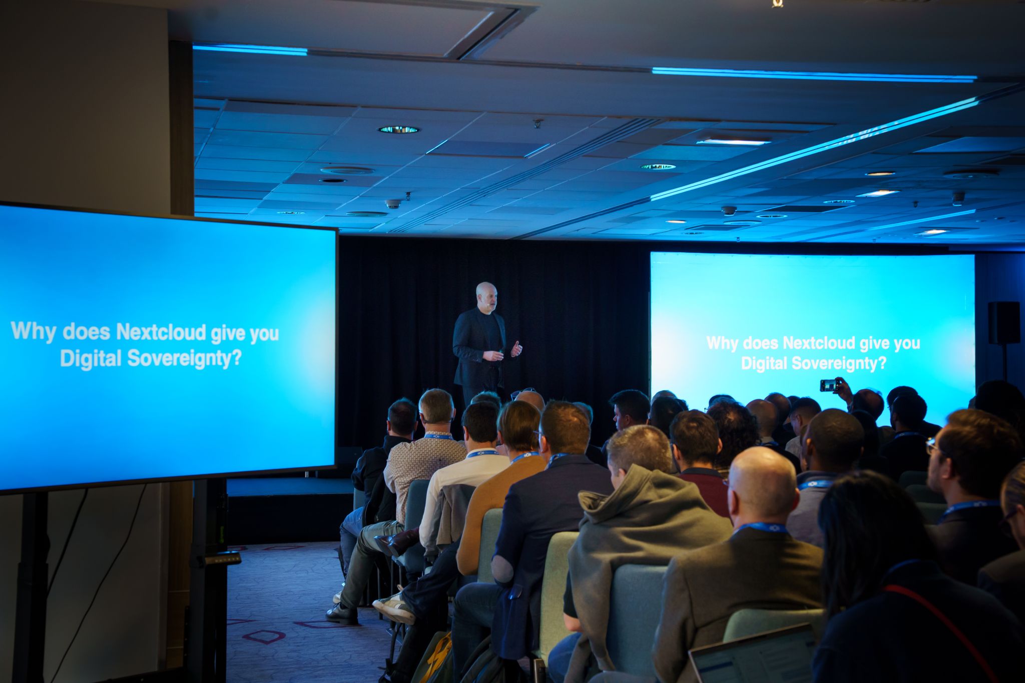 Frank Karlitschek speaking to a crowded room with a screen behind him