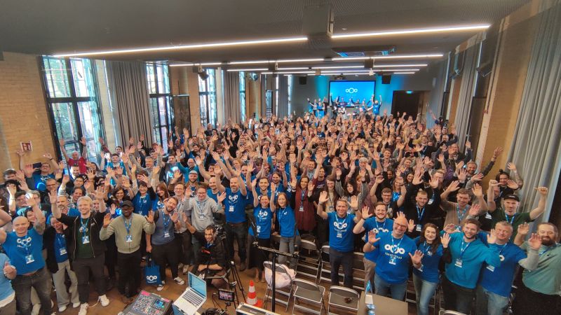 photo of a large group in Nextcloud branded t-shirts with their arms in the air