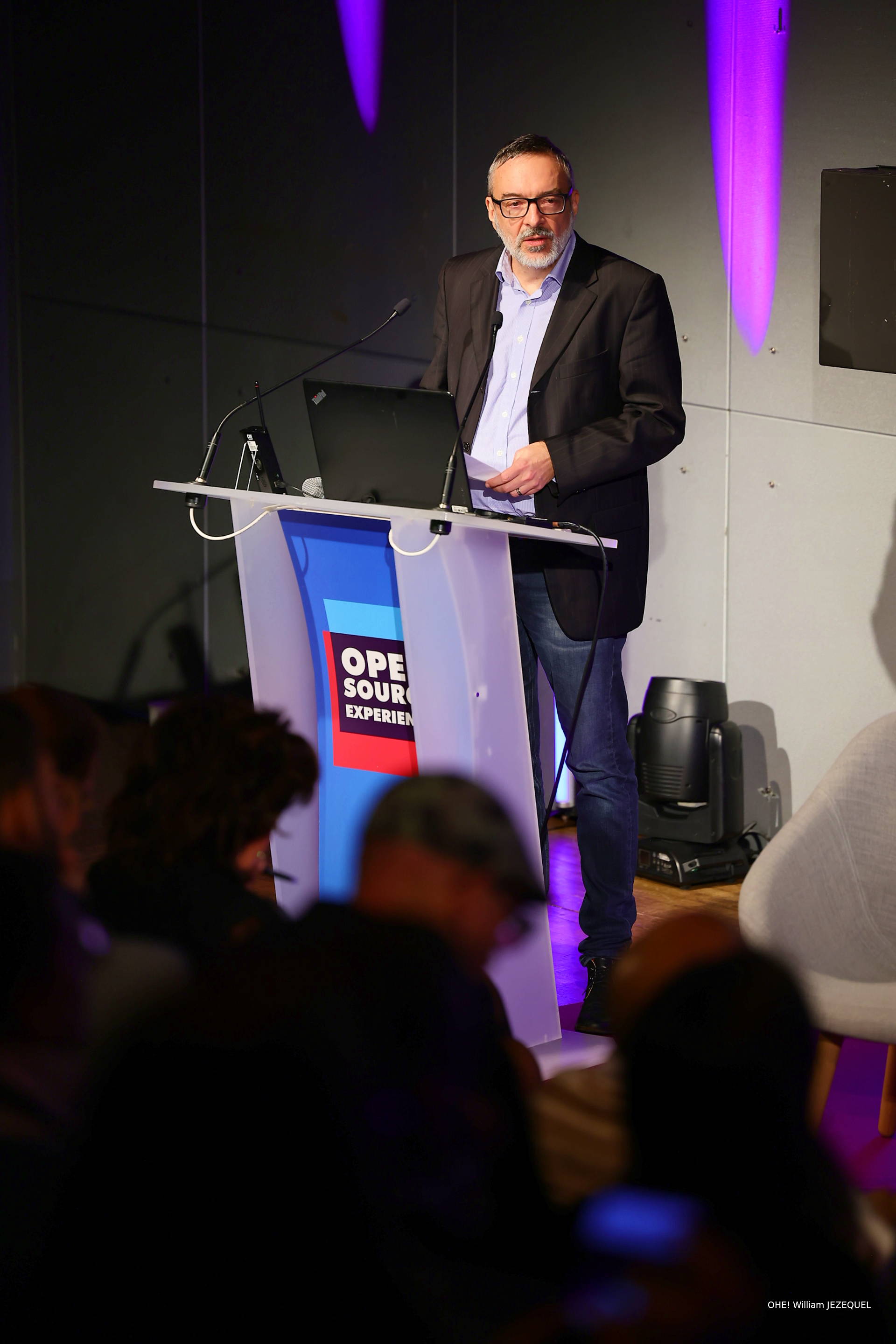 Photo of Stéfane Fermigier speaking at a podium with the words 'Open Source Experience' on the front